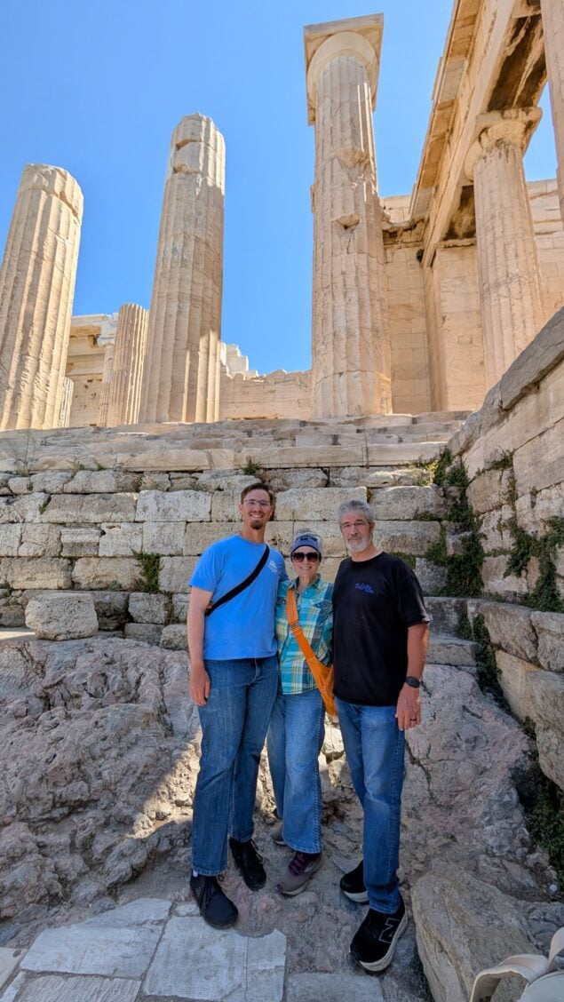 three tourists in front of the Parthenon ruins in Athens